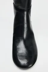 Bota negra de caña media de cuero sintético, con punta redonda y tacón ancho.