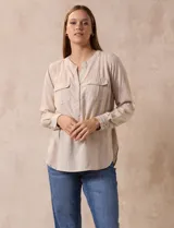 Blusa beige de lino y rayón, marca Dash. Tiene cuello a la base, escote en V y abertura con botones. Delantera con bolsillos. Largo de manga regulable con presilla y botón.