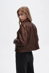 Chaqueta marrón de eco-cuero, corte recto, con cierre asimétrico y cuello solapa.