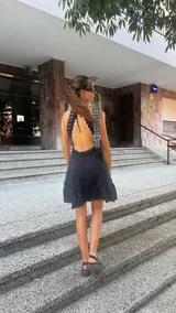 Vestido corto negro con espalda descubierta y detalles de encaje en los tirantes.