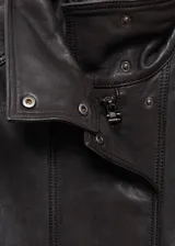 Chaqueta negra de cuero ovino con cuello alto abotonado, corte recto y bolsillos de solapa con botón en el frente.