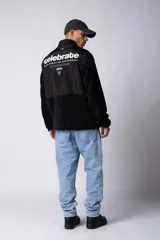 Campera negra con la parte superior de tela tipo rompevientos con dos bolsillos con solapa y la parte inferior de micro polar. Tiene cierre frontal y cuello alto.