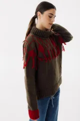 Sweater tejido de punto color crudo con cuello alto y diseño de rombos marrones con flecos.