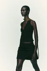 Falda pantalón negra de tiro alto con delantero cruzado y pliegues. Cierre trasero con cremallera oculta.