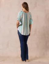 Blusa estampada de rayas verticales en tonos verde, celeste, amarillo y naranja, con cuello cuadrado, escote en V con aplique metálico y bordado con brillos. Tiene mangas cortas amplias y terminación con nudo en el ruedo.
