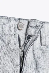 Pantalón de jean de tiro medio con pierna ancha y corte tapered, confeccionado en tejido de algodón revestido color gris claro. Cuenta con bolsillos delanteros y traseros, trabillas en la cintura y cierre frontal con cremallera y botón.
