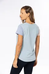 Remera de manga corta color beige con bloque de color en mangas: celeste en la manga izquierda y rosa en la manga derecha.
