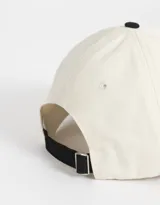 Gorra de béisbol bicolor, con cuerpo de canvas color crema y visera de gamuza color marrón. Tiene bordado frontal con la palabra "Wednesday" y el número "1996".