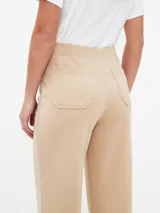 Pantalón beige de corte acampanado con bolsillos delanteros con solapa y botón.