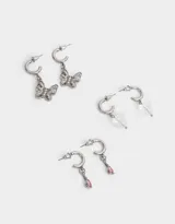 Set de tres pares de aros argolla plateados con dijes colgantes: gota rosada, mariposa con strass y corazón transparente.