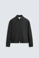 Sobrecamisa negra de lana con cuello solapa, manga larga con puños abotonados, bolsillos de vivo en la cadera y cierre frontal con cremallera.