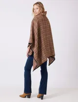 Ruana tejida de la marca Jones New York, con estampado a cuadros en tonos marrón, beige y blanco. Presenta cuello alto y cierre frontal con botón trenca y botón a presión interno. Los bordes están ribeteados en negro.
