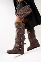 Botas altas color marrón claro, de cuero gamuzado, con caña alta y múltiples correas horizontales con hebillas metálicas.