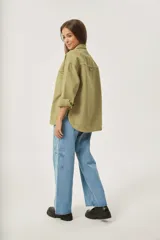 Sobrecamisa azul de jean con corte holgado, cuello camisero, cierre con botones a presión y dos bolsillos de parche en el pecho.