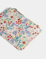 Tarjetero de cuerina con estampado floral multicolor, cierre superior con cremallera y bolsillo frontal abierto.