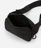 Riñonera negra con cierre de cremallera, correa ajustable y logo de la marca en relieve. Fabricada con poliéster reciclado.