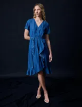 Vestido de tencel azul con escote en V cruzado, cintura elastizada con lazo, manga corta con volados y falda midi con volados.
