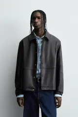 Cazadora de efecto piel color marrón oscuro, corte relajado, con cuello solapa, cierre frontal de botones a presión y bolsillos de vivo en cadera.