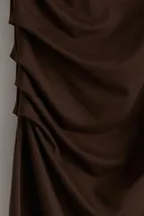 Vestido corto marrón de punto elástico, con cuello elevado corto, mangas cortas y corte ajustado. Presenta pliegues en un hombro y en un lateral para crear un efecto drapeado.