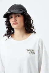 Remera blanca de corte holgado con mangas cortas y cuello redondo. Estampado pequeño en el frente con la frase "Spritz and Shine" en verde.