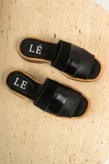 Sandalias de cuero negras con diseño de tiras cruzadas y detalle de elástico en el talón.