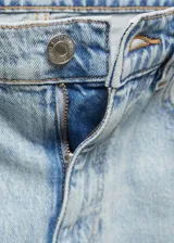 Pantalón de jean celeste de tiro alto, corte mom fit, con cinco bolsillos, trabillas y cierre de cremallera con botón.