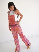 Jardineros de cuero con estampado artístico en tonos fucsia, naranja y rosa.