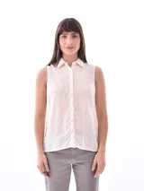 Camisa sin mangas color crudo con cuello clásico, cierre frontal con botones y diseño calado vertical.