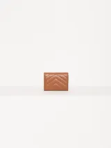 Billetera pequeña color visón, con solapa y cierre a presión. Diseño acolchado con pespuntes en forma de V y logo metálico con forma de labios.