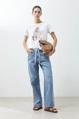 Remera blanca de algodón con estampa de motivos playeros en tonos marrones.