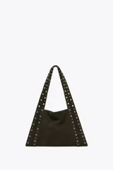 Bolso de hombro negro de serraje con tachas metálicas doradas en el cuerpo y las asas. Tiene un bolsillo interior y doble asa de hombro. Se cierra con un botón imantado.