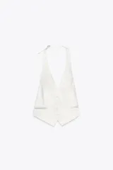 Top chaleco blanco de tejido satinado con cuello halter ajustable con hebilla metálica, falsos bolsillos de doble vivo en delantero, espalda descubierta con tira ajustable y cierre frontal con botones.