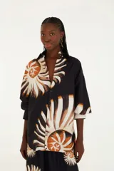 Camisa negra con estampado de amonitas, cuello mao, botones frontales ocultos y mangas largas ligeramente acampanadas.