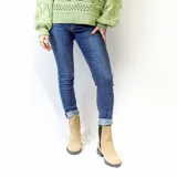 Bota Chelsea blanca de cuero sintético con elástico lateral negro adornado con tachas plateadas. Tiene suela track negra y taco bajo.