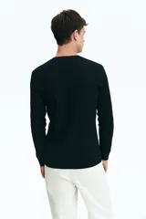 Remera negra de manga larga en punto waffle de mezcla de algodón de peso medio. Modelo con cuello redondo y ribete acanalado en cuello y puños.