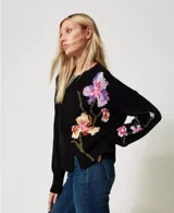 Sweater negro de algodón con cuello redondo, manga larga y corte holgado. Presenta incrustaciones florales decoradas con bordados a mano.
