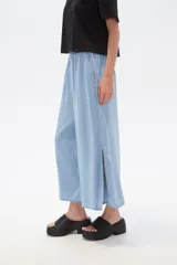 Pantalón capri de denim azul con cintura elástica y aberturas laterales en el ruedo.