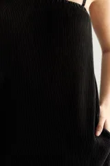 Vestido negro plisado con breteles finos y escote elástico.