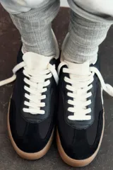 Zapatillas deportivas de mujer con combinación de materiales en negro, blanco y marrón. Cierre con cordones y suela en contraste color caramelo.