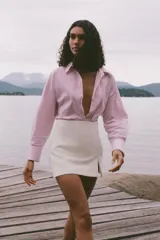 Camisa de popelín a rayas verticales rosas y blancas con hilo metalizado, de corte recto, cuello solapa, escote pico y manga larga.
