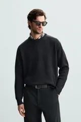 Jersey negro de punto con cuello redondo y manga larga. Presenta parches combinados en hombros y codos.