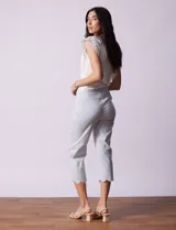 Pantalón capri marca Zac & Rachel, confeccionado en gabardina elastizada a rayas verticales celestes y blancas. Presenta pretina ancha elastizada y ruedo con bordado floral.