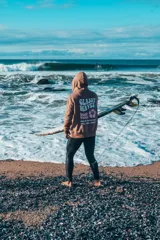 Buzo hoodie marrón con capucha y cordones ajustables. Estampado en la espalda con la frase "Glassy Waves", "Good Vibes" y una flor.