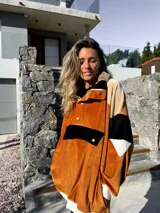Buzo de terciopelo color tostado, beige y negro, con cierre de media cremallera, cuello alto con botones a presión y bolsillo tipo canguro con solapa y botón.