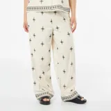Pantalón ancho color beige con bordado de cruces negras.