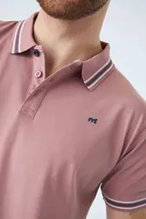 Remera cuello polo blanca de piqué, corte regular, manga corta, logo estampado y terminaciones a contratono en cuello y mangas con rayas rojas, grises y azules.