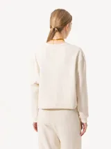 Buzo de punto color crema con lurex y mangas largas con puños ajustados.