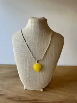 Collar con cadena plateada y dije de corazón amarillo.
