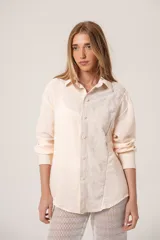 Camisa oversize color crema, de manga larga confeccionada en mezcla de lino y algodón. Presenta diseño bicolor con panel frontal bordado, cartera de botones y cuello clásico.