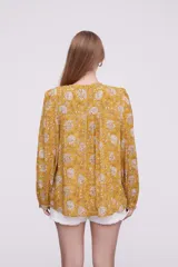 Blusa holgada con estampado floral en tonos amarillos y blancos, de manga larga.